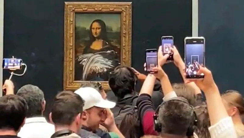 Man dressed as an elderly lady throws a cake at the Mona Lisa painting in Paris.